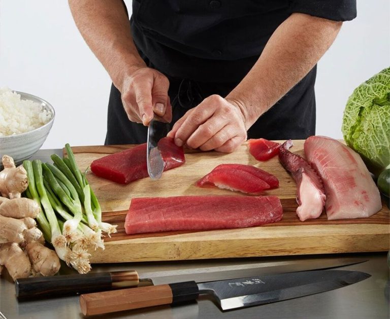 a chef slicing pieces of raw fish for sushi