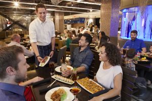 Kona Grill restaurant full of people enjoying sushi, burgers, and cocktails.