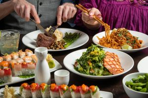 Dining table full of delicious food including sushi, steak and noodles